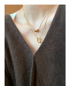 Close-up of double layered gold titanium steel necklaces with horseshoe and bead charms