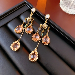 Macro shot of gold tassel earrings with peach teardrop crystal and starburst detail