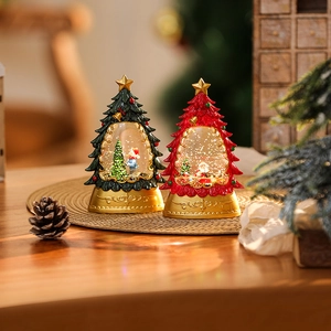 Close-up of Christmas tree snow globes with Santa and snowman figures on a wood base