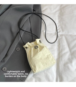 Close-up of cream white drawstring crossbody bag featuring textured lightweight nylon fabric