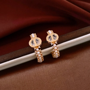 Detail of 18k gold plated hoop earring with CD logo and white pearls on silk
