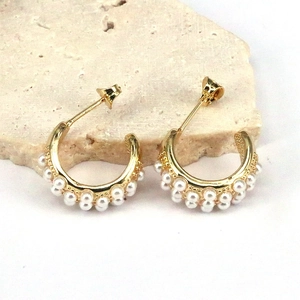 Detailed close-up of gold C-shaped hoop earrings with elegant double-row faux pearl inlay