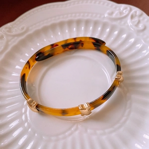 Detailed view of leopard print resin bangle with gold metallic accents on ceramic plate