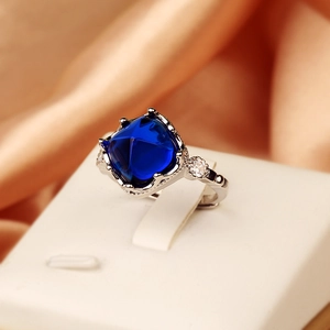 Luxurious silver ring with large sugarloaf blue sapphire and diamond accents on white stand