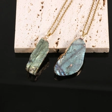 Detailed close-up of two natural blue kyanite gold plated pendants on a stone surface