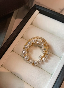 Macro shot of 24k gold-plated round brooch with pearls and zircons in a jewelry box