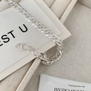 Detail of S925 sterling silver chain bracelet with polished Cuban links on beige fabric