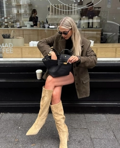 Street style shot of a dark brown suede blazer paired with chic beige pointed tall boots