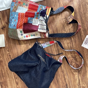 Detail of vintage patchwork canvas bag and blue denim embroidery on wood background