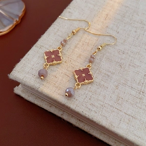 Close-up of vintage gold clover earrings with brown enamel and crystals on linen