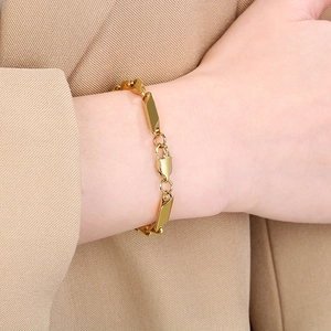 Gros plan d'un bracelet en acier inoxydable doré avec fermoir mousqueton au poignet