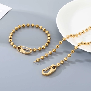 Detailed macro view of 6mm golden ball chain with spring clasp closure on grey surface