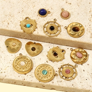 French style gold heart and evil eye pendants with natural stone inlay on stone background