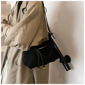 Detail view of black suede half-moon crossbody bag with elegant gold metal tip buckle
