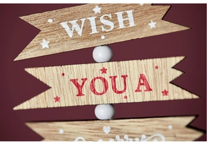 Macro shot of wooden Christmas arrow sign with white beads and festive Merry Wish text