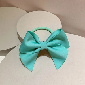 Detail of mint green ribbed ribbon bow hair tie displayed on a geometric stone base