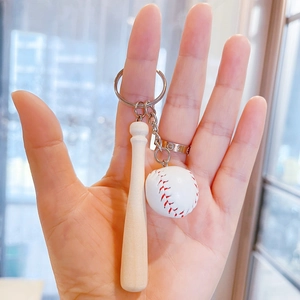 Macro detail of mini wooden baseball bat and stitched ball keychain held in hand