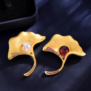 Elegant gold ginkgo leaf brooch pair with ruby red crystals on dark blue silk