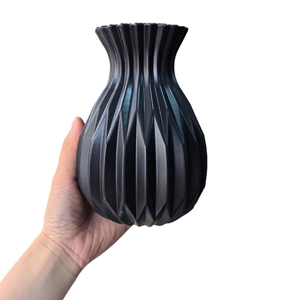 Modern black geometric origami flower vase held in hand to show size on white background