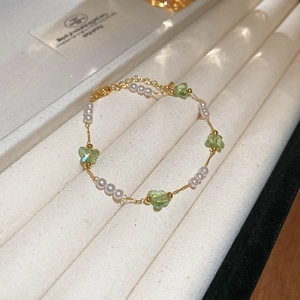 Detail of freshwater pearl bracelet with green butterfly charms and gold-tone chain