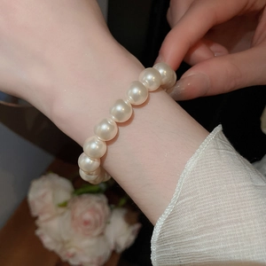 Détail du bracelet en perles blanches et plaqué or 18 carats porté au poignet