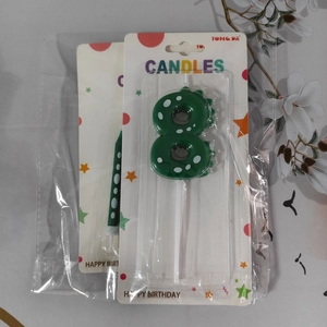 Detail of green dinosaur number 8 candle with white polka dots in clear packaging