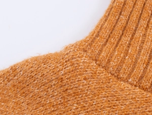 Dettaglio del colletto in maglia a costine arancione con morbida texture pelosa