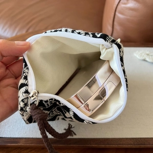 Macro view of geometric embroidered small pouch showing zipper and canvas interior