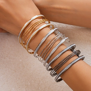 Detailed macro of layered metal bracelets in gold, silver, and black matte finish