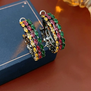Macro shot of vintage hoop earrings with multicolored zircons on a dark metal base