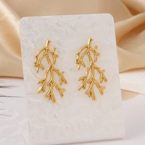 Golden sea grass branch earrings in stainless steel on white marble stand with silk background