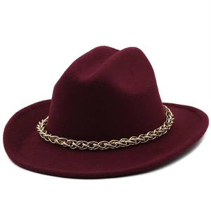 Detail of burgundy fedora hat featuring a chunky gold metal chain on wool felt