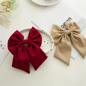Elegant large bow hair clips in burgundy and beige fabric on a minimalist background