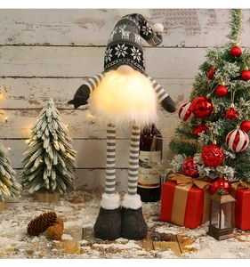Close-up of a glowing Christmas gnome featuring long striped legs and a warm LED light