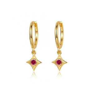 Macro view of gold hoop earrings featuring a star pendant and red zircon stone