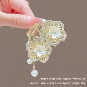 Gros plan détaillé de la pince à cheveux fleur dorée avec strass et pompons de perles