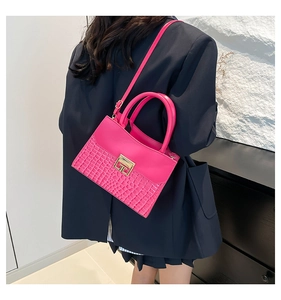 Detail showing fuchsia crocodile pattern handbag with gold square lock on a model