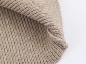 Macro view showing the soft texture and ribbed knit pattern of light brown knitwear