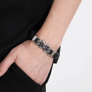 Detailed shot of a black braided leather bracelet featuring silver metal skull charms