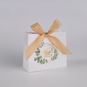 Detail of white wedding favor bag with gold Thank You text and green eucalyptus leaf