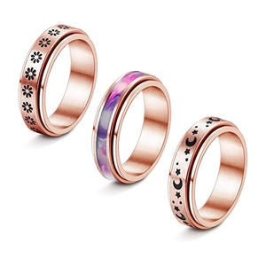 Detail of rose gold spinner rings with moon, stars, and daisy engravings in brushed finish
