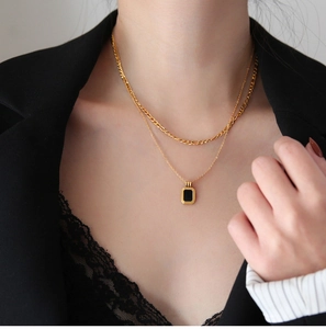 Double-layered gold titanium steel necklace with black square pendant on a female model