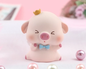 Close-up of cute pink resin piglet ornament with golden crown and blue bow decoration