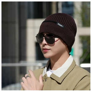 Outdoor shot of a man wearing a thick dark brown knit beanie with a stylish black logo