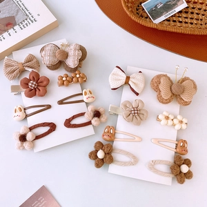 Dettaglio di fermagli in peluche marrone e beige con motivi di fiori e coniglietti