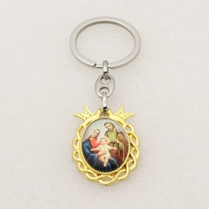 Detail of religious Holy Family keychain featuring silver ring and golden oval pendant