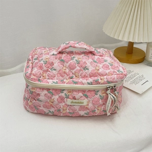 Detail of pink floral quilted fabric makeup bag with top handle and zipper closure