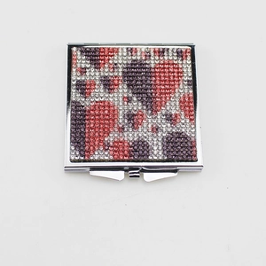 Close-up of folding makeup mirror with sparkling red, purple, and white rhinestones