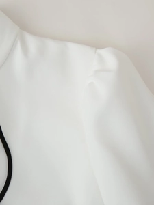 Macro detail of elegant shoulder pleats and white woven texture on puff sleeve dress