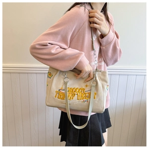 Beige canvas tote bag with colorful star embroidery and adjustable shoulder strap